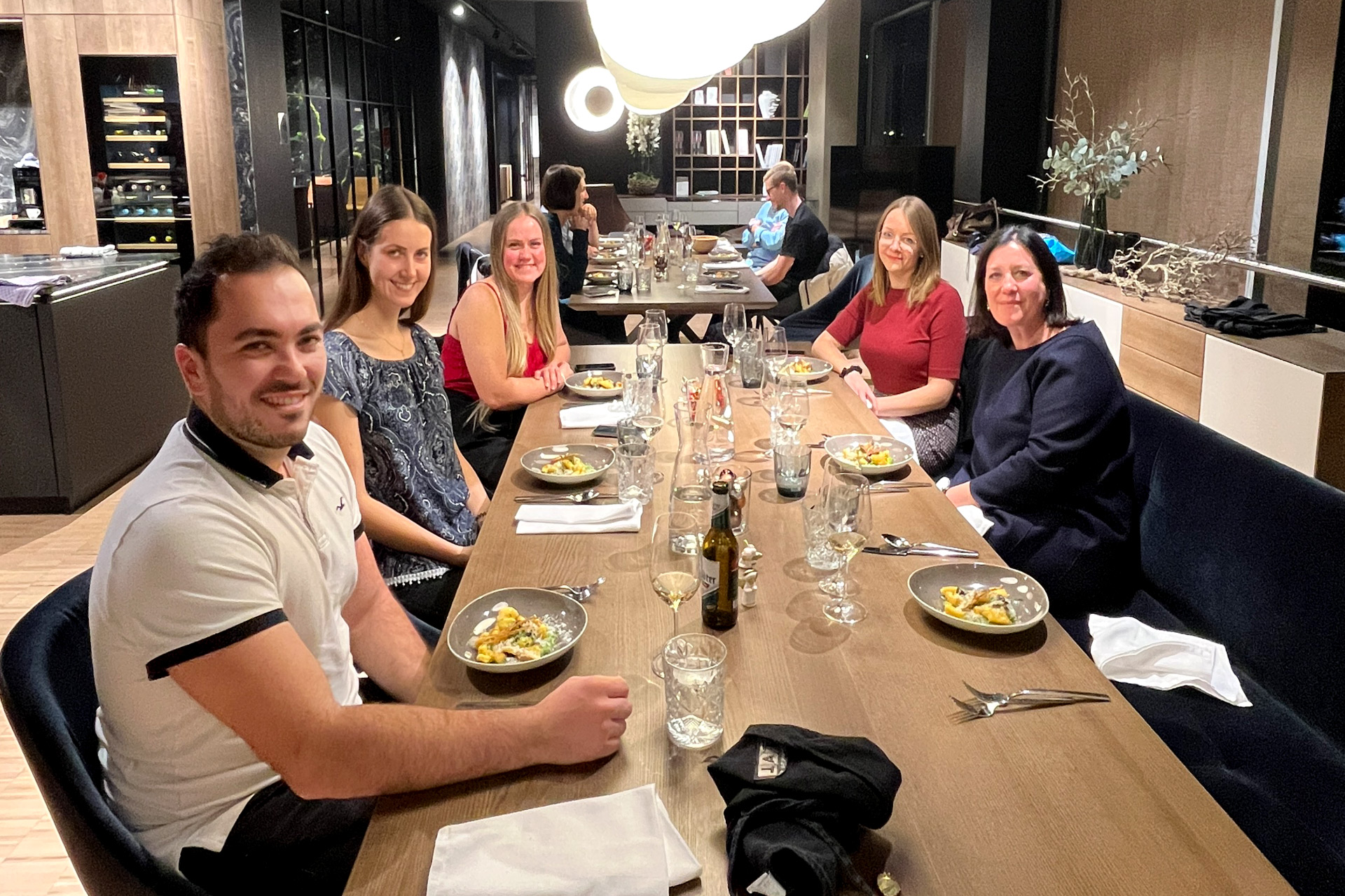 Das Digitrans-Team versammelt sich zu einem festlichen Weihnachtsfeier-Dinner in einem stilvollen Speisesaal, genießt gutes Essen, Wein und warme Gesellschaft.
